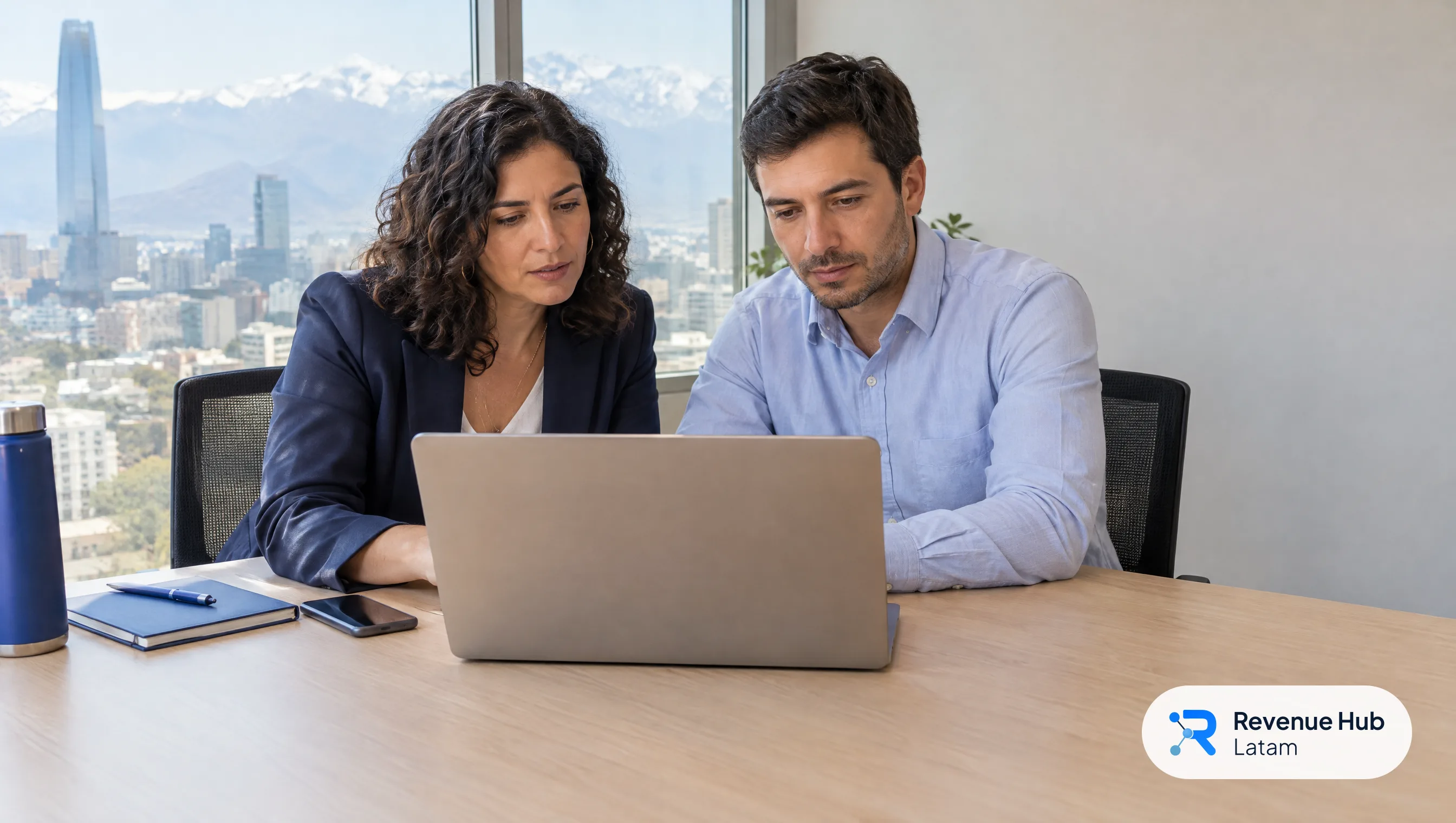 Una gerente de marketing y un gerente comercial revisan juntos un acuerdo en un notebook en una sala de reuniones en Santiago